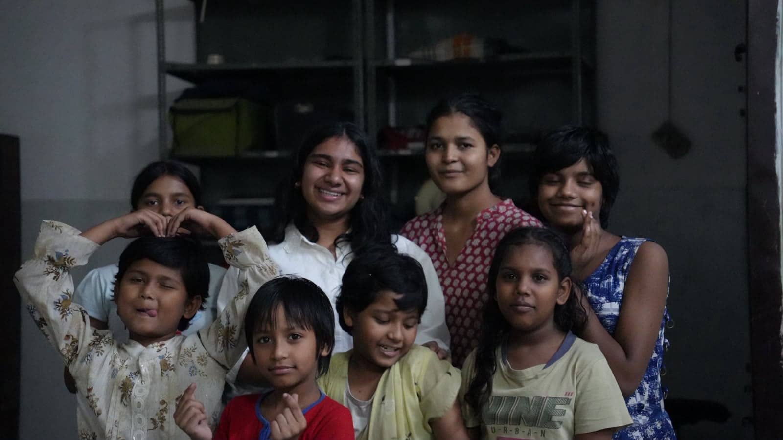 Children and volunteers smiling for the camera in a community centre room.