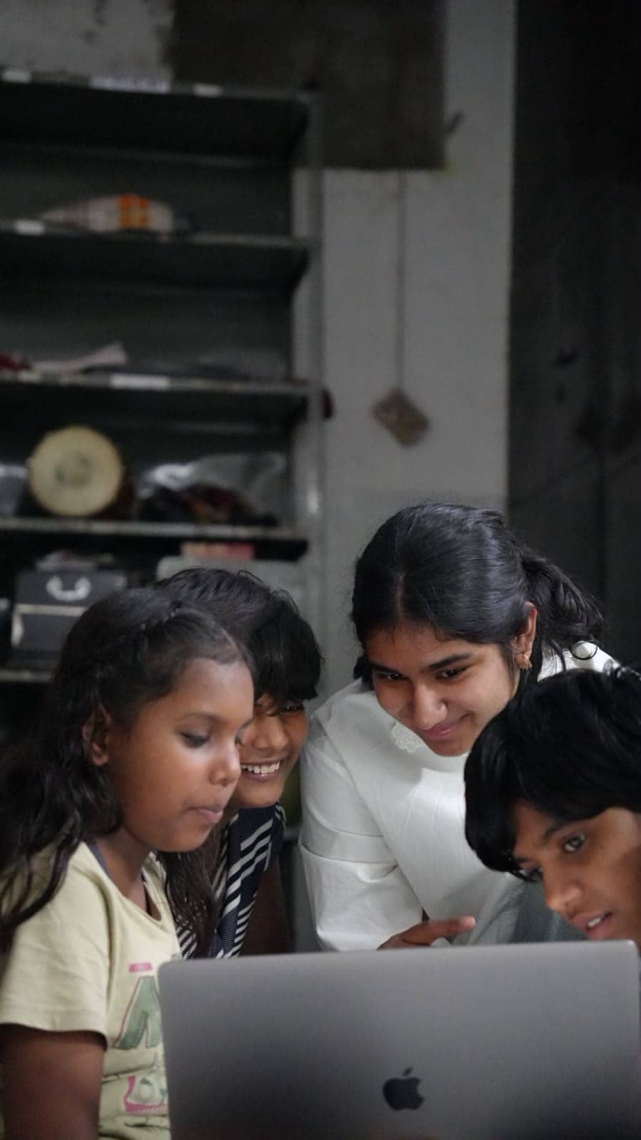 Girls gather round a laptop with a volunteer.